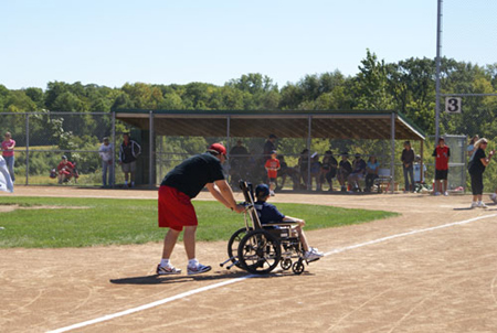 A South Metro Miracle League player rounds the bases with help from his ‘buddy’.